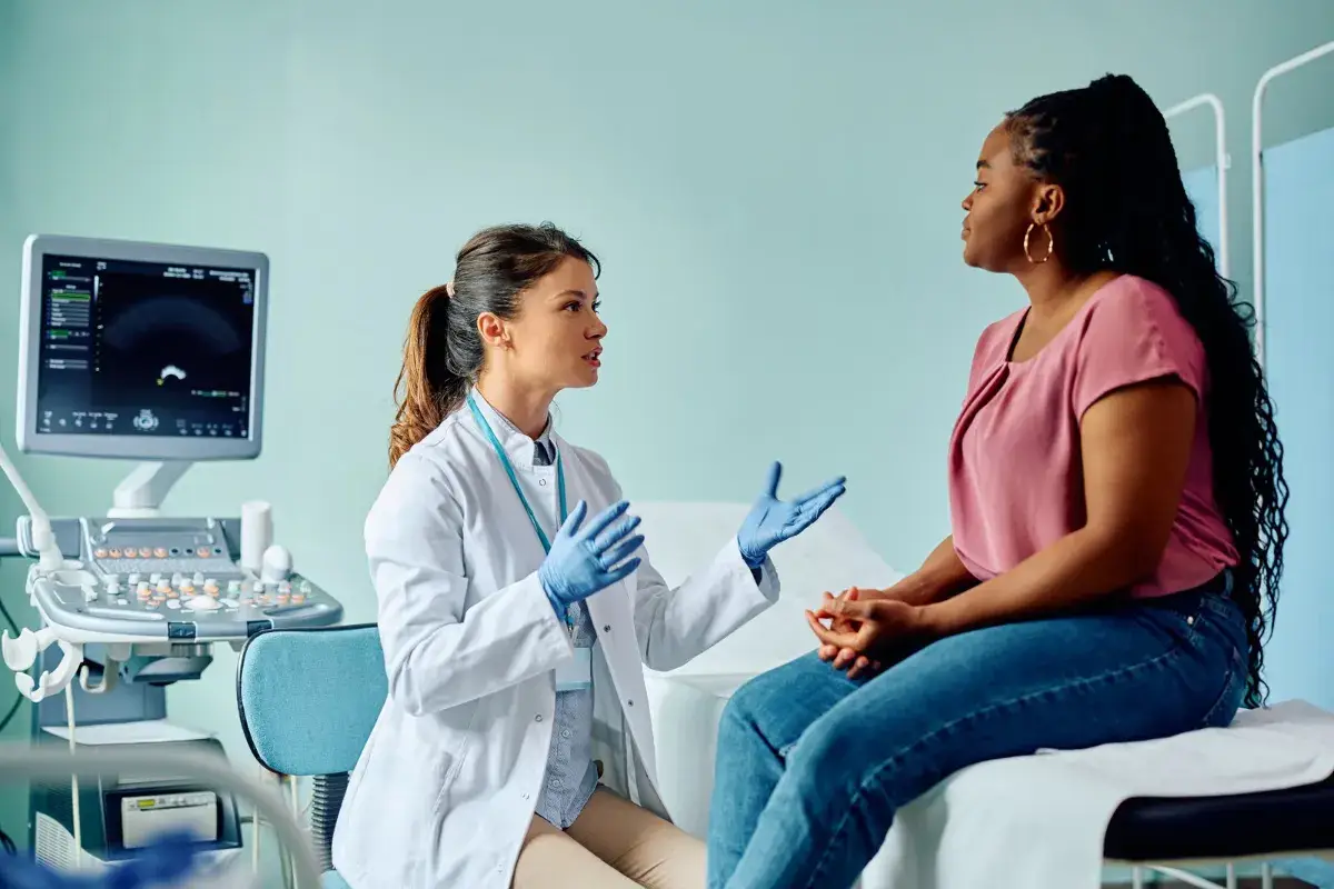 Woman discussing uterine fibroid symptoms with a physician in an ultrasound exam room