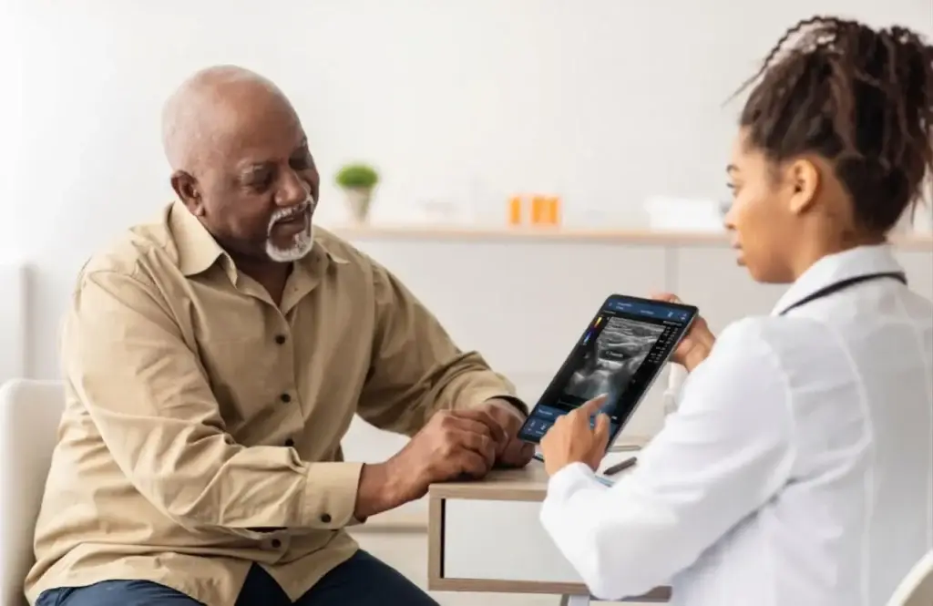 VidaVascular clinician showing a senior patient his vein ultrasound results on a tablet